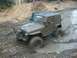 1979 Ford Bronco - This off-road vehicle is navigating a challenging muddy terrain, kicking up water and mud as it goes.