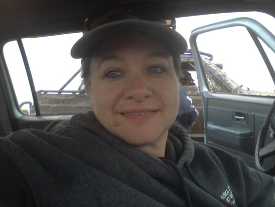 Woman wearing a baseball cap and hoodie inside a light blue pickup truck cab