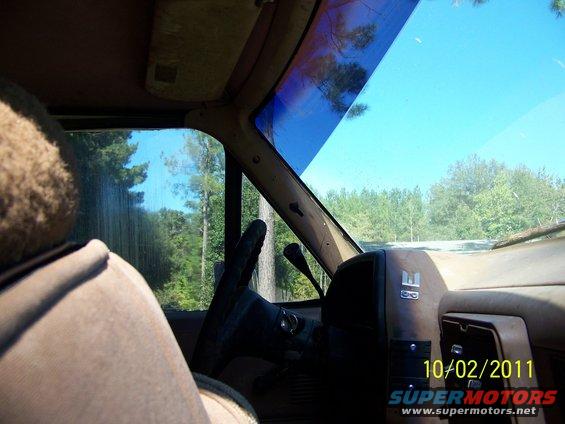 Inside an old SUV, looking out the windshield at trees. There's a steering wheel and part of the dashboard