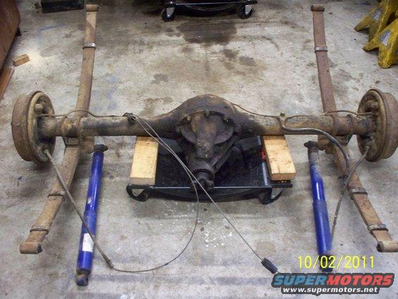 Rear axle assembly with leaf springs and shocks, sitting on a dolly
