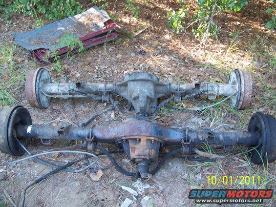 Two rear axles with drum brakes, one lighter colored, one rusty