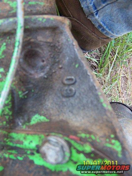 Metal casting with '60' stamped, green paint, bolt, grass, and jeans