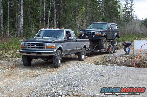 Gray Ford F-250 towing a black Ford Bronco on a trailer