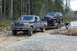 1995 Ford F-250 - A Ford F-250 tows a lifted Ford Bronco on a trailer through a wooded area.