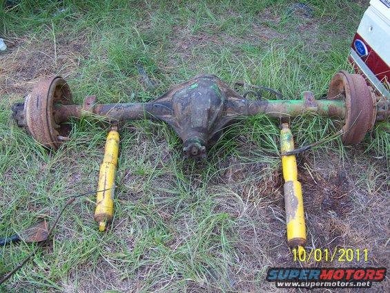 Ford Dana 60 rear axle with two yellow shocks, sitting on grass