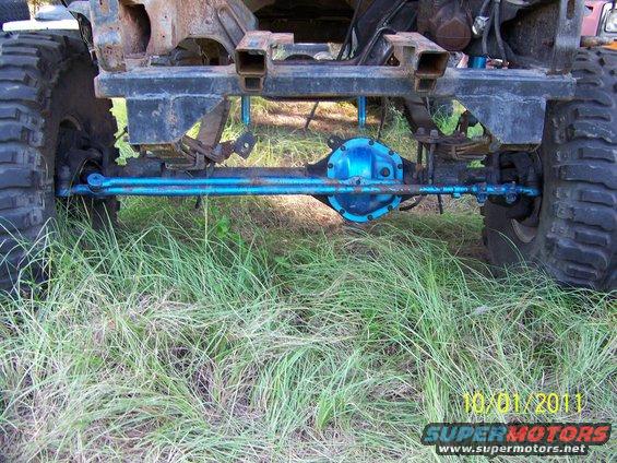 Close-up of a blue-painted rear axle assembly with suspension components and large tires