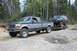 1995 Ford F-250 - A 1995 Ford F-250 pickup truck tows a lifted SUV on a trailer through a wooded area.