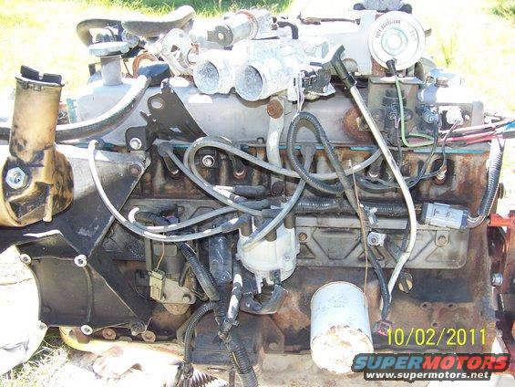 Engine block with spark plug wires, oil filter, and distributor cap. Some rust is visible