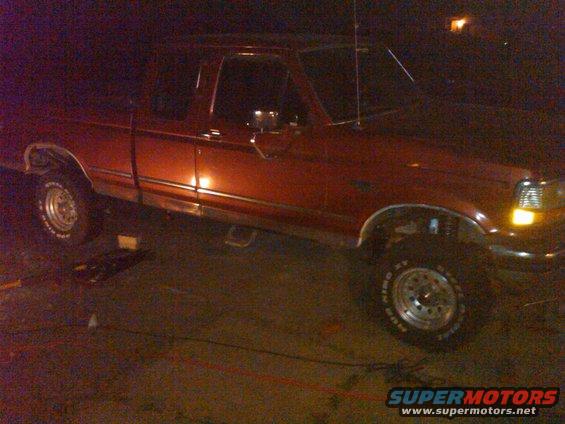 Red 1992 Ford F-150 pickup truck, side view, with a lift kit installed