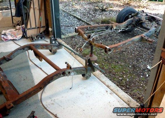 rusted vehicle frame on jack stands, with one tire visible