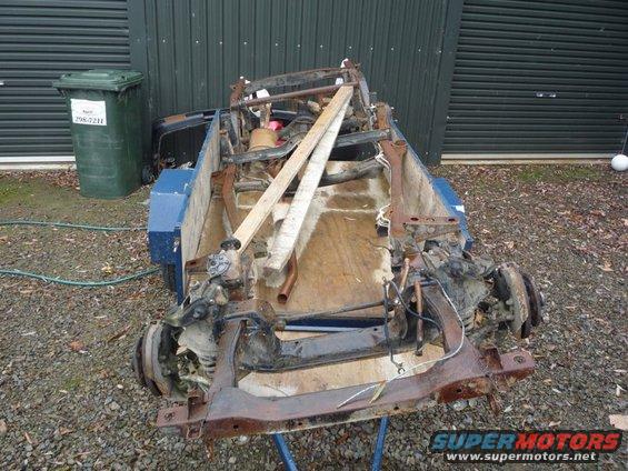 Car chassis on trailer, front view. Some wooden supports are visible