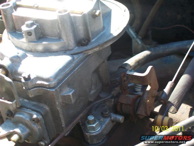 Close-up of a carburetor with throttle linkage and springs