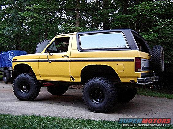 Yellow Ford Bronco with lifted suspension and large tires parked outside