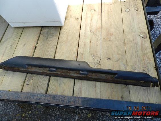 Black plastic trim piece with metal backing on wooden planks