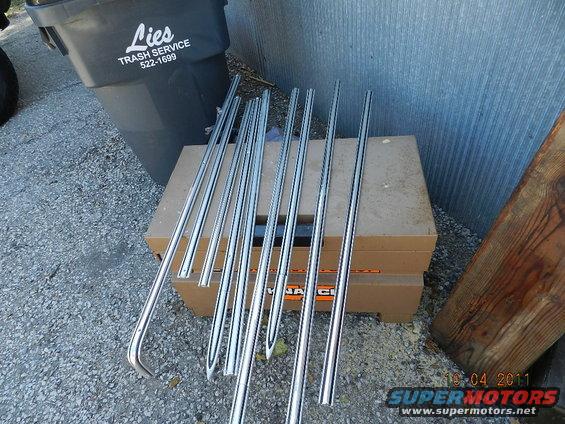 pile of chrome trim pieces on top of cardboard boxes next to a trash can