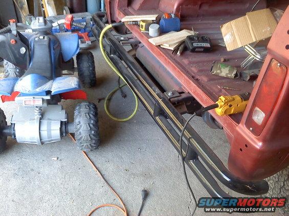 Red vehicle bed with running boards, ATV, and power tools. Watermark "SUPERMOTORS.NET"