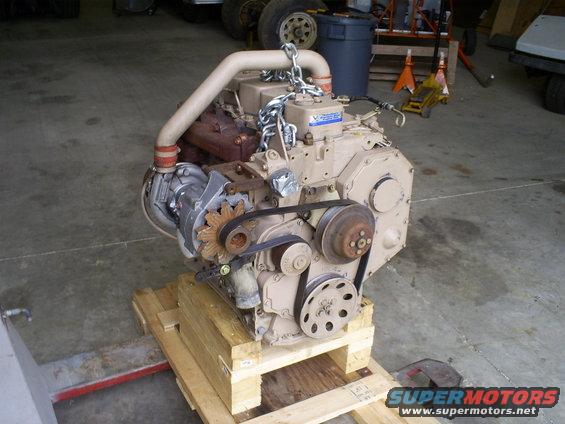 Tan engine with turbocharger and belts on wooden pallet