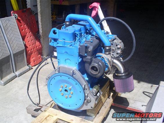 Blue engine with turbocharger and purple air filter on a wooden pallet