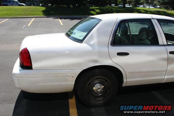 White sedan parked in a lot, showing the rear quarter panel and side