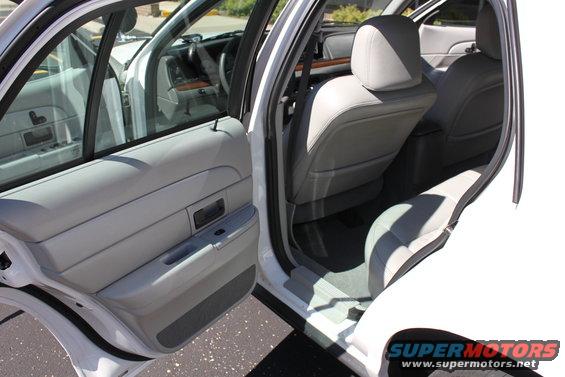 White sedan interior with gray leather seats and door panels. Watermark reads SUPERMOTORS.NET