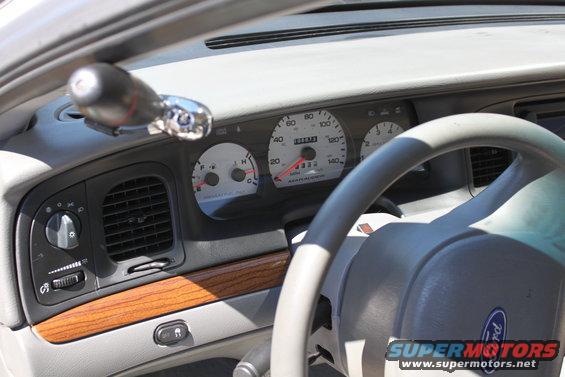 Dashboard of a 2003 Ford Crown Victoria, showing the steering wheel, instrument cluster, air vents, and gear shifter
