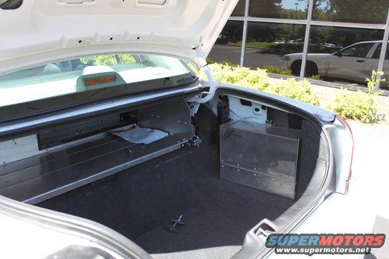White 2003 Ford Crown Victoria trunk interior with metal storage boxes and a document