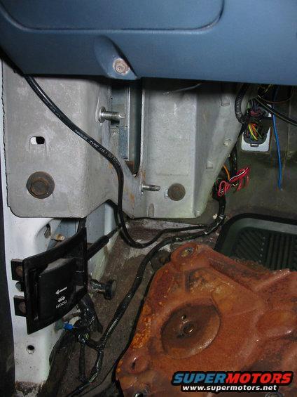 Under dash wiring and a rusty metal component, possibly part of the HVAC system