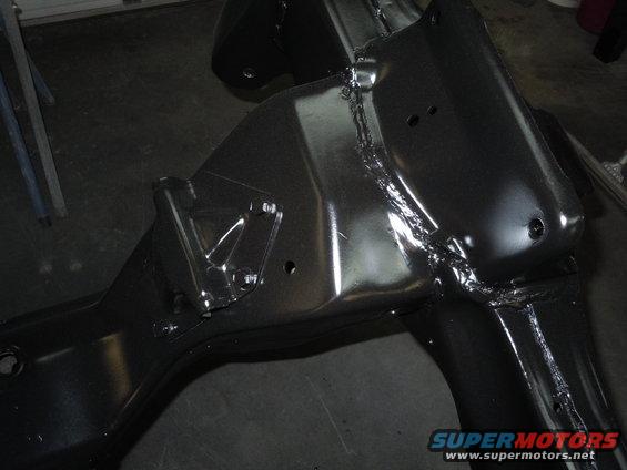 Close-up of a black painted car frame section with visible welds