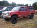 1991 Toyota Pickup/SR5 - Red 1991 Toyota Pickup/SR5 with camper shell and roof rack is parked next to another truck.