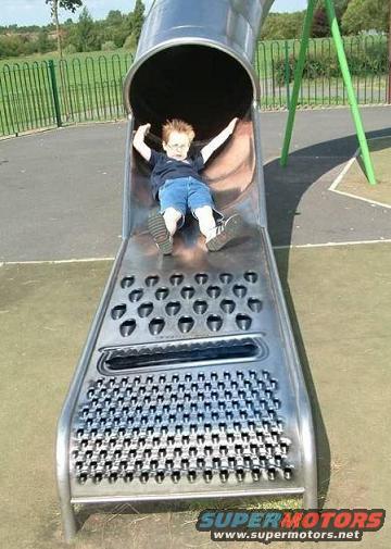 Child sliding down a metal slide resembling a cheese grater