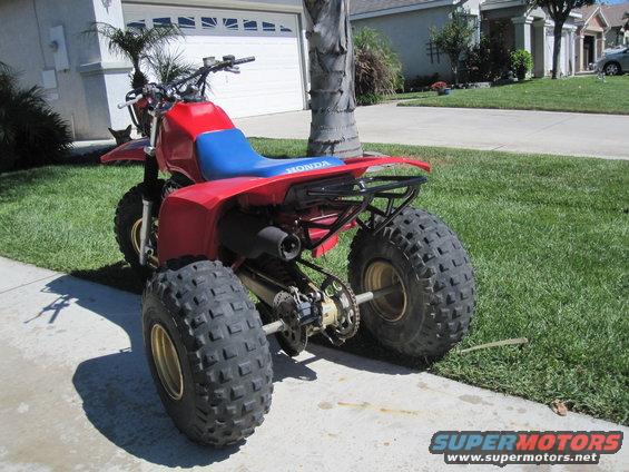 1983 Honda 250 R ATV, red body with blue seat, parked on a driveway