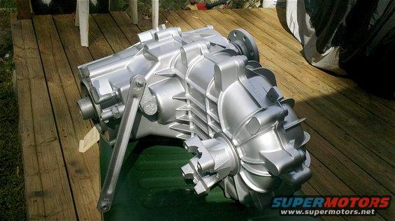 silver transfer case sitting on a green surface on a wooden deck