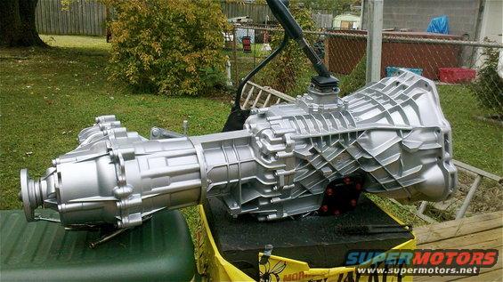 ZF5 transmission and transfer case assembly, painted silver, resting on a black block and yellow tarp