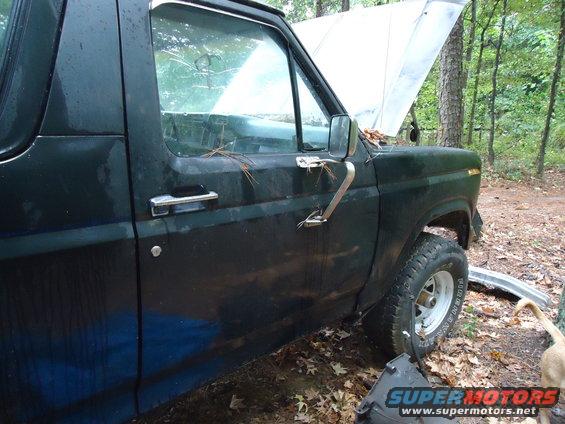 Dark green Ford Bronco side view, hood open, showing door handle and tire