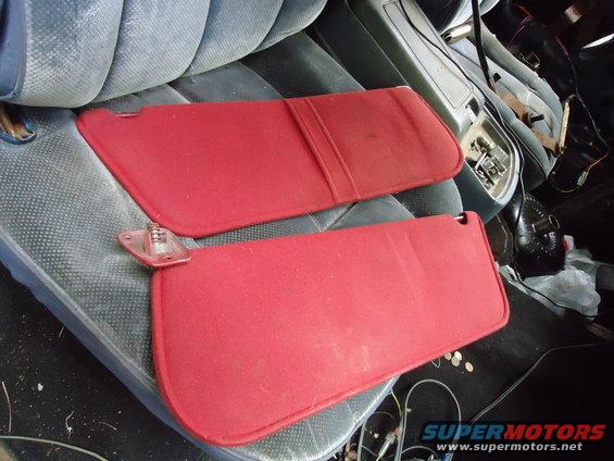Two red sun visors resting on blue seats inside a vehicle