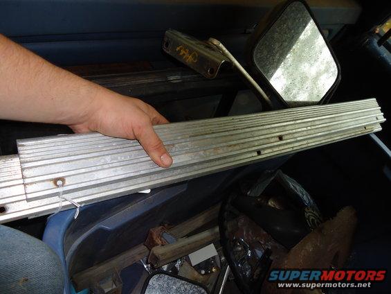 Aluminum trim piece held by hand, interior parts scattered
