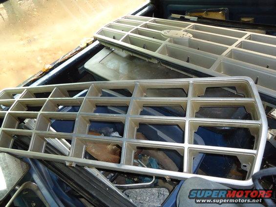 Two vehicle grilles are stacked in the bed of a truck