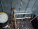1985 Ford Bronco - A rusty driveshaft and a chrome bull bar are visible next to a metal wall and some buckets.