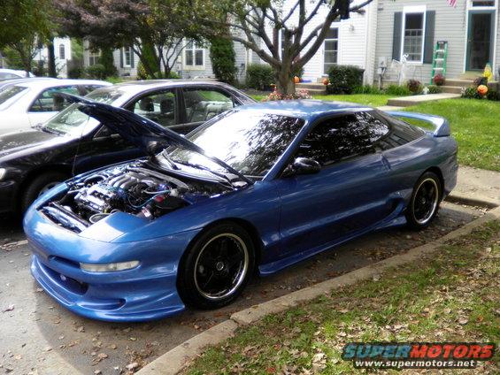Blue coupe with hood open, engine visible. Modified body kit