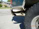 1996 Ford Bronco - A close-up view of a vehicle's rear tire and exhaust pipe, with a house in the background.