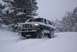 1996 Ford Bronco - A two-tone Ford Bronco navigates a snowy, wooded area during a snowfall.