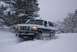 1996 Ford Bronco - A Ford Bronco navigates a snowy road with trees in the background.