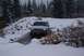 1996 Ford Bronco - A silver Ford Explorer navigates a snowy, watery path in a wooded area.