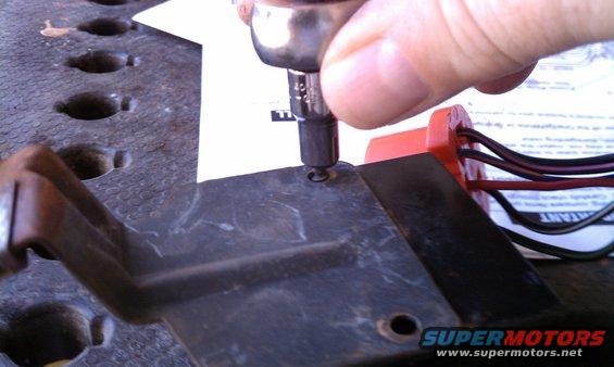 socket wrench tightening screw on black plastic part with wires
