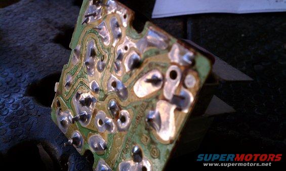 Close-up of a green circuit board with silver solder points and traces