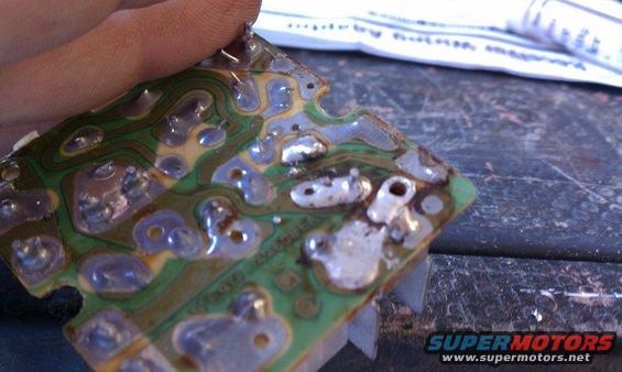 Circuit board with visible solder points and traces, held by a hand
