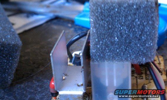 Close-up of an electronic component with a metal heatsink and black foam padding, wires visible
