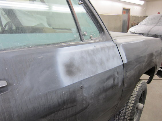 Side view of a 1987 Dodge 1500 truck with primer on the body panels, showing the door and fender area