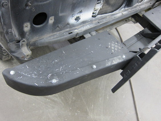 Black step bumper with silver bolts, showing wear