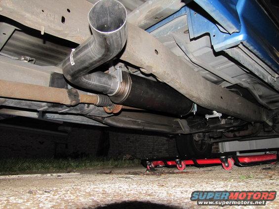 Underneath view of a custom exhaust system with a large muffler and chrome tip